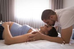 gestante deitada na cama com marido dando um beijo na sua testa