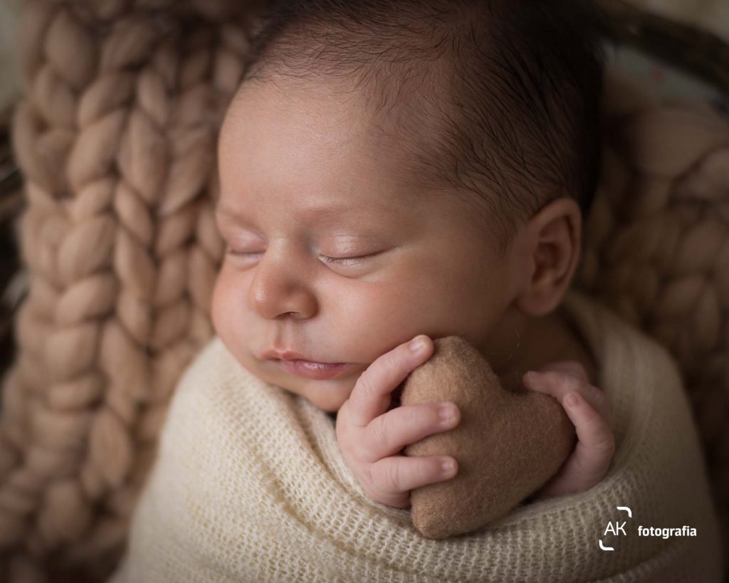 newborn bebe enrolado wrap segurando coração de feltro