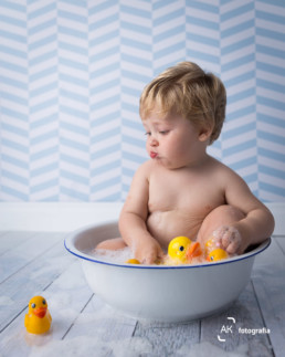 bebê tomando banho com balde e patinhos