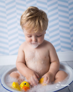 bebê tomando banho de balde com patinhos