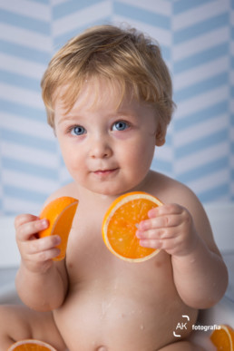 bebê segurando laranjas milk bath