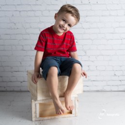 menino sentado em caixas de madeira