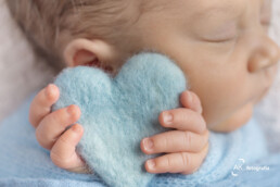 bebê segurando um coração azul em seu ensaio newborn