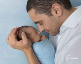 pai segurando o seu bebê recem nascido durante ensaio newborn